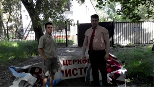 Andrew Zhuravlev, the minister for the Central Church of Christ, and his son IIya standing in front of a church sign ripped off by the insurgents. May 25, 2014