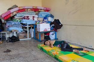 Boy lying in classroom, pile of mattresses in the corner. Primary school in Erbil where refugees of Qaraqosh are housed. 