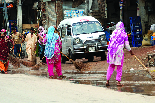 Christian sweepers remove water from the road after rain in Lahore.