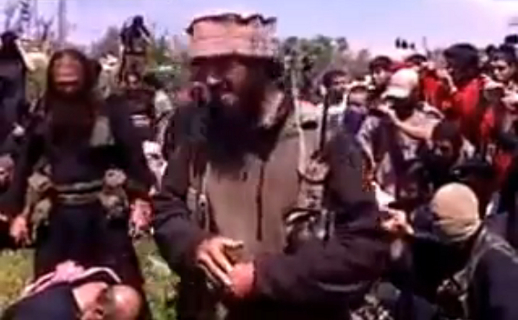 In this undated image taken from a video posted in 2013, a man whom Turkish intelligence identified as Magomed Abdurrahmanov, foreground, is seen speaking to a crowd moments before he decapitates one of three men identified as Christians.