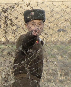 North Korean border guard at fence on Yalu Border between China and North Korea. 