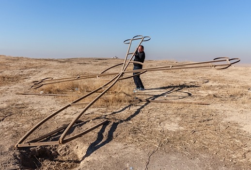 Fr. Thabet on a hill outside Karamles, picking up a cross toppled by Islamic State.