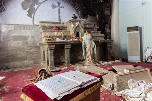 A decapitated statue of the Virgin Mary stands in front of the altar of this badly damaged church.