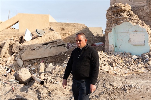 Father Thabet walks amongst the rubble in Karamles, his hometown.
