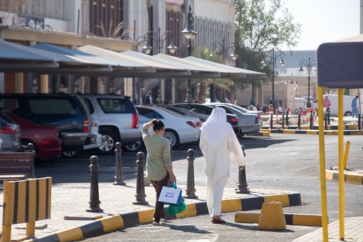 A Kuwaiti man walks in front, trailed by an Asian woman.