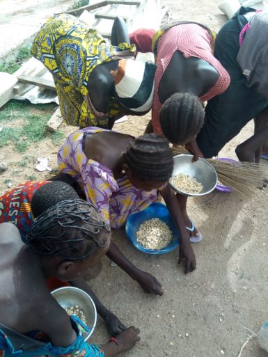 Children at a location for food distribution pick up fallen grain. (Photo: Open Doors International)