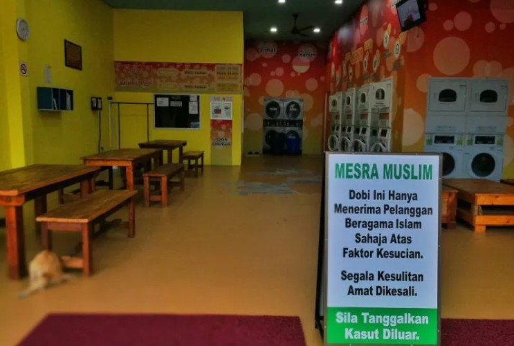 Laundrette sign translates as: "For Muslim customers only. Leave your shoes outside.”