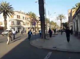 People running in the streets of Asmara while gun shots can be heard.