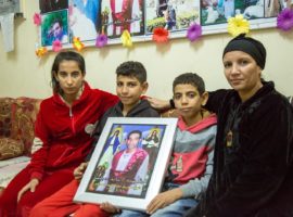 Marco and Mina with their mother and elder sister hold portrait of their father who died in 25 May attack. (Photo: World Watch Monitor)