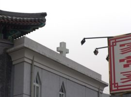Cross of a state-sanctioned Three-Self church in Beijing is visible just above the facades of the city while China's government is trying to get more control over house churches. (Photo: World Watch Monitor)