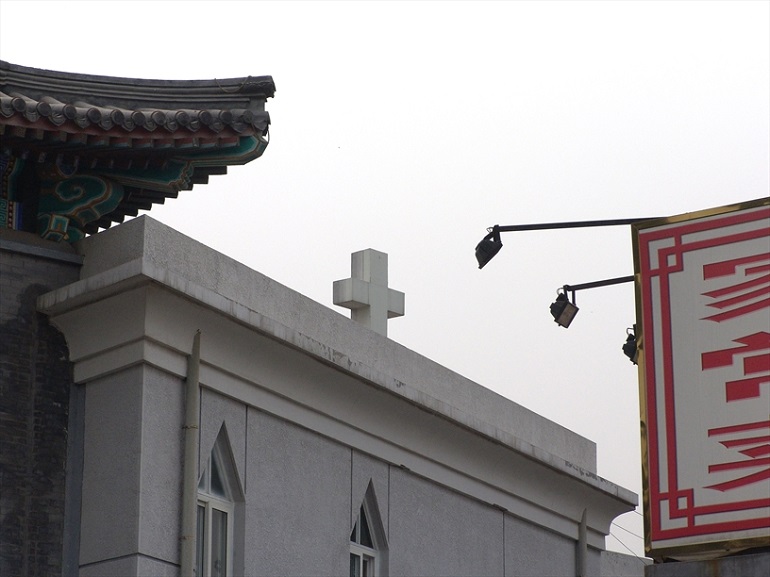 Cross of a state-sanctioned Three-Self church in Beijing is visible just above the facades of the city while China's government is trying to get more control over house churches. (Photo: World Watch Monitor)
