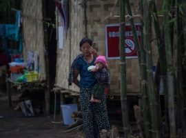 An internally displaced woman with a child stands near a temporary shelter in a church compound in Kachin's capital Myitkyina. (Photo: YE AUNG THU/AFP/Getty Images)